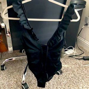 This is a black one-piece bathing suit with cute ruffles at the top.